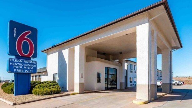 Um motel com placa visível indicando comodidades como quartos limpos, piscina aquecida interna e acesso Wi-Fi gratuito.