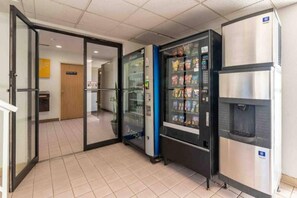 A vending machine area with a refrigerator and a door leading to another room.