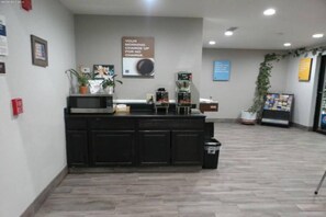 A reception area with a counter, a fire extinguisher, a sign, and a plant.