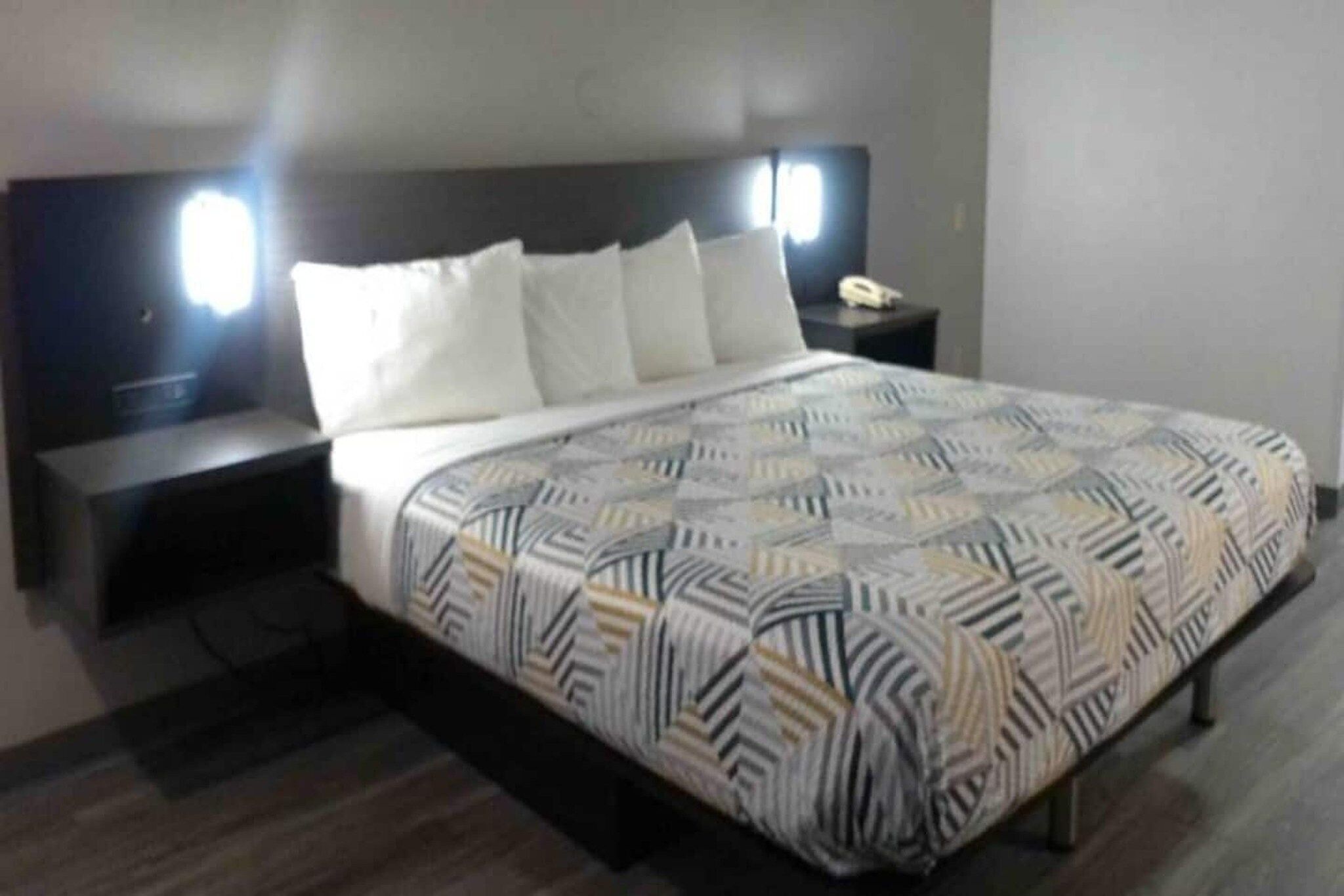 A hotel room with a bed, nightstands, and a telephone.