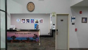 Uma área de recepção com um relógio, quadros decorativos, uma placa indicando a sala 66 e um cartaz promocional para um aplicativo móvel.