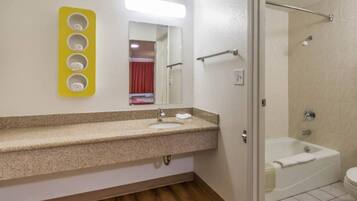 Un baño con lavamanos, espejo y zona de ducha.