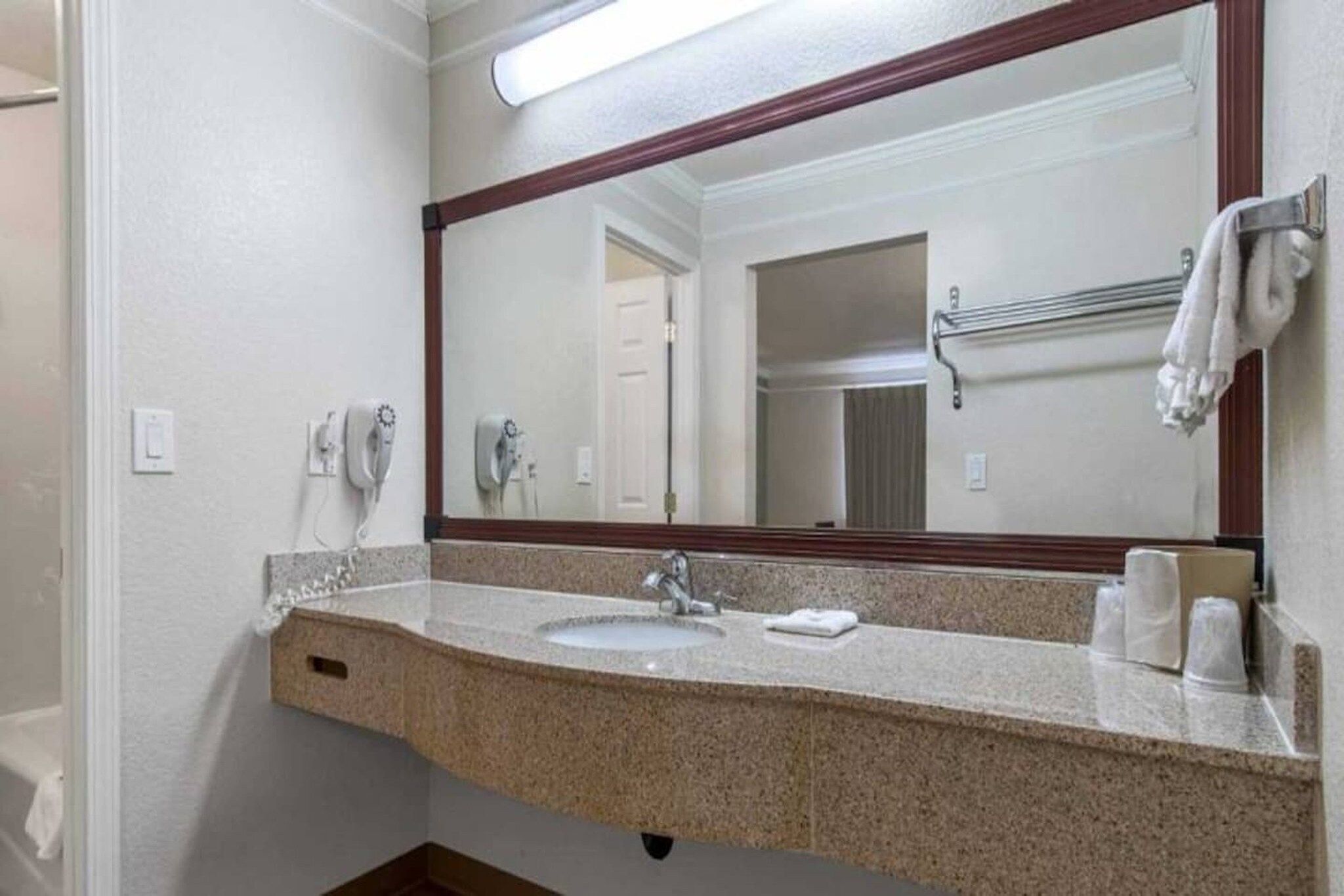 A bathroom with a granite countertop, a sink, a mirror, and a towel rack.
