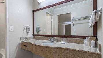 A bathroom with a granite countertop, a sink, a mirror, and a towel rack.