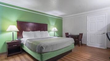 Una habitación de hotel con cama, mesitas de noche, escritorio y una silla.