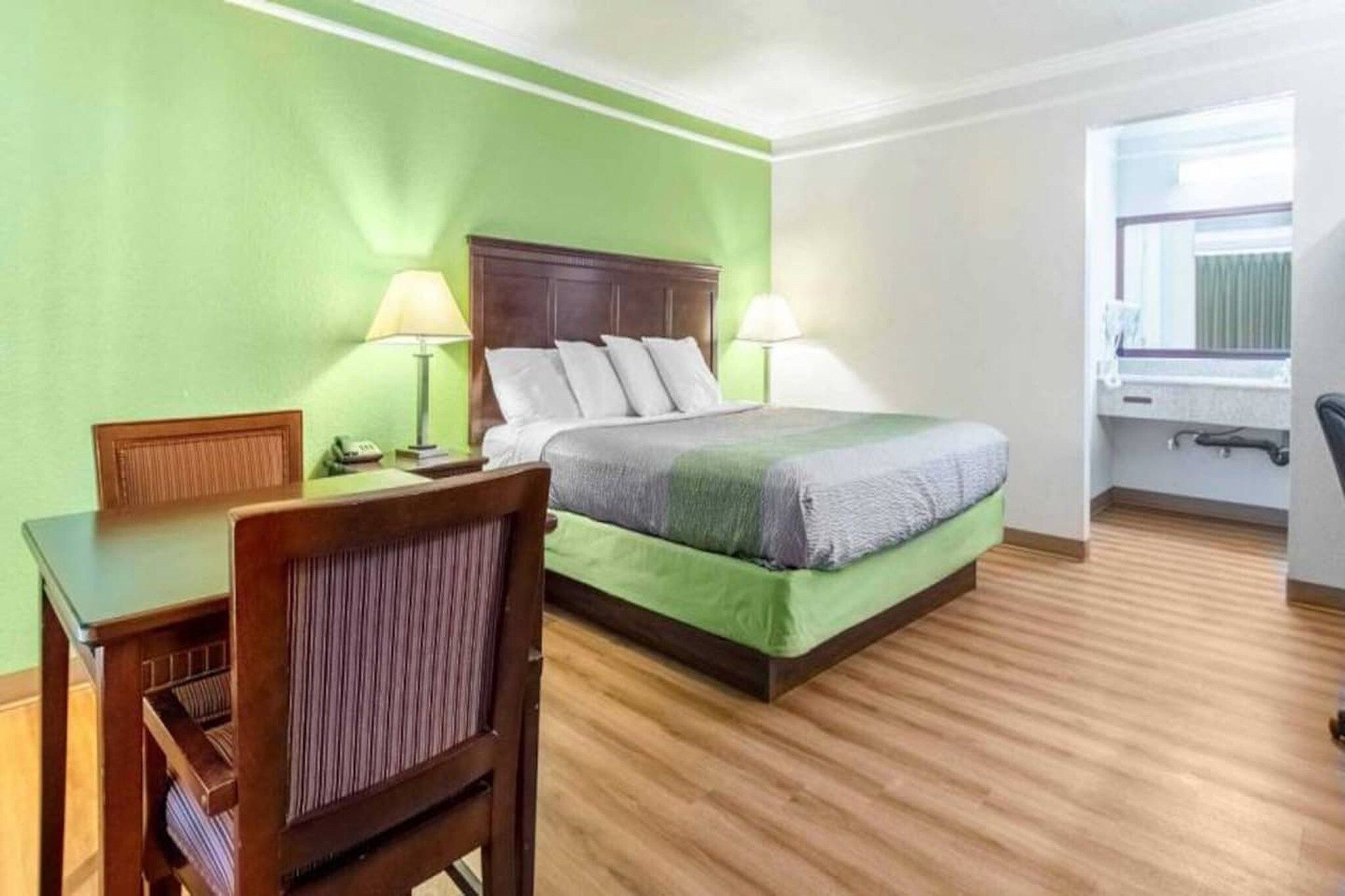 Una habitación de hotel con una cama, lámparas de noche, un escritorio y una silla.