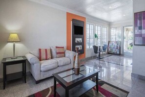 A modern living room with a sofa, a coffee table, a lamp, and a TV. - Premium King Bed|Pool|Free Parking (Kingsburg)