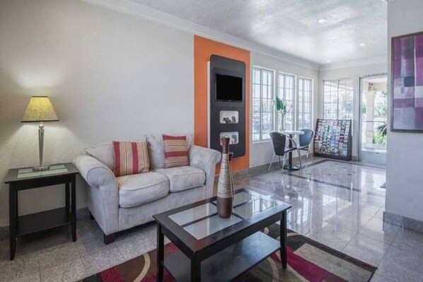 A modern living room with a sofa, a coffee table, a lamp, and a TV.