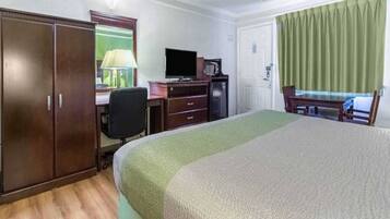 Een hotelkamer met een bed, een bureau met stoel, een televisie en een kledingkast.