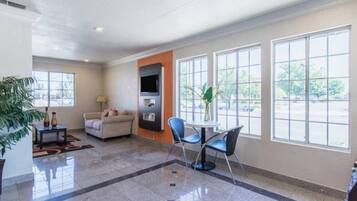 A spacious lobby with a sofa, chairs, a coffee table, and a TV.