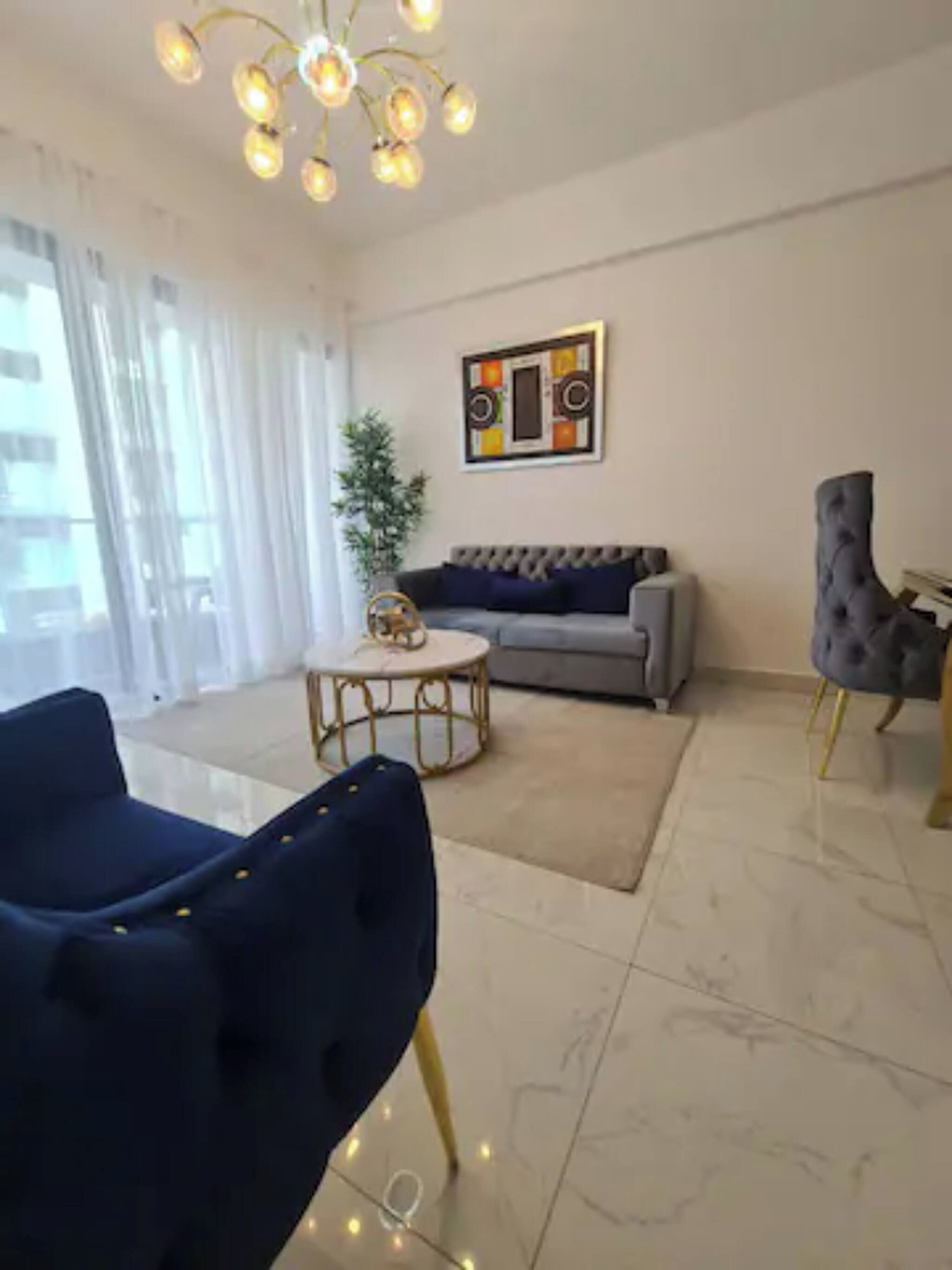 Un salon moderne avec un canapé, une table basse ronde et un fauteuil bleu.