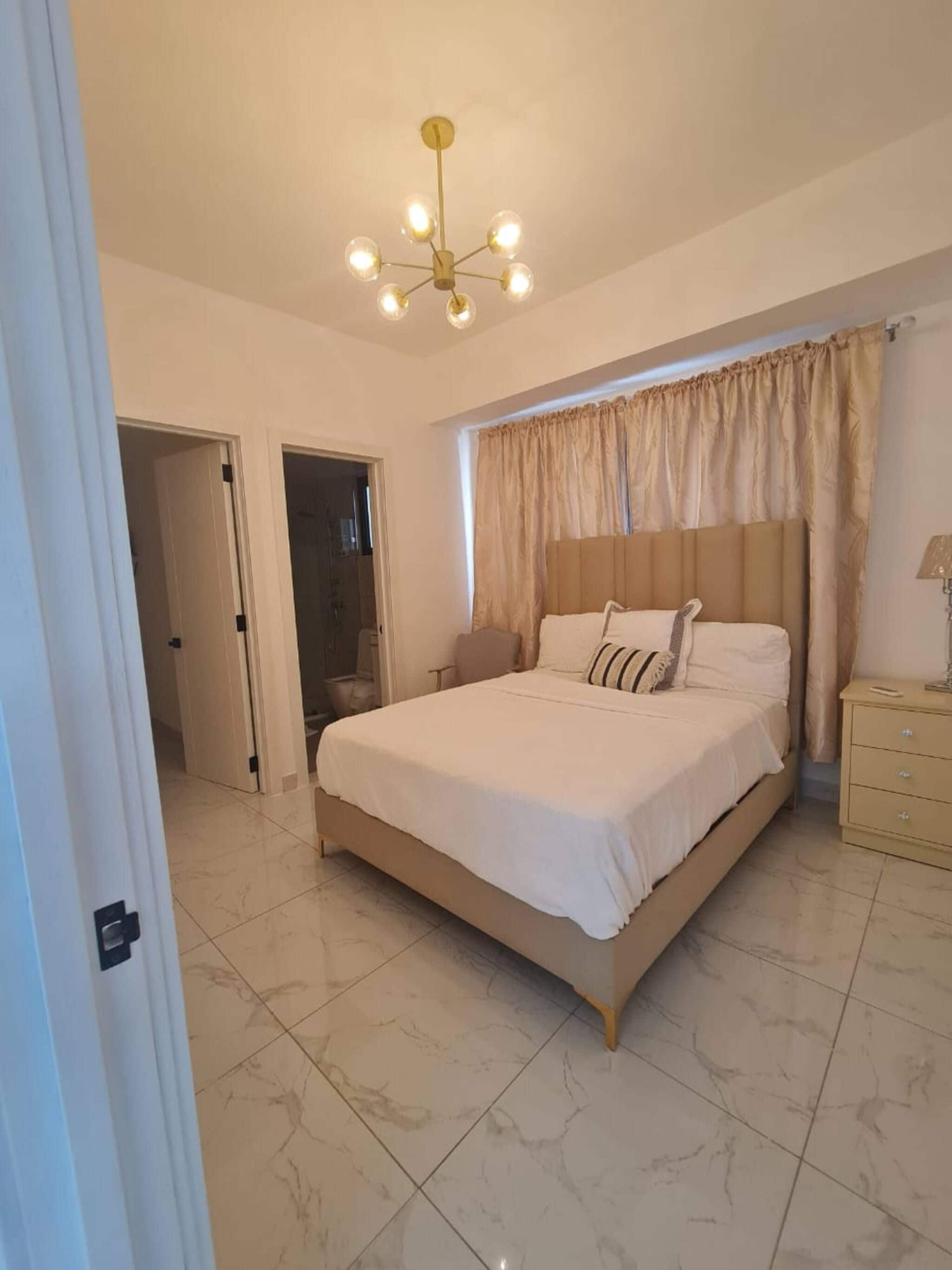 A bedroom with a bed, a bedside table, a lamp, and a ceiling light fixture.