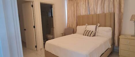 A bedroom with a bed, a bedside table, a lamp, and a ceiling light fixture.