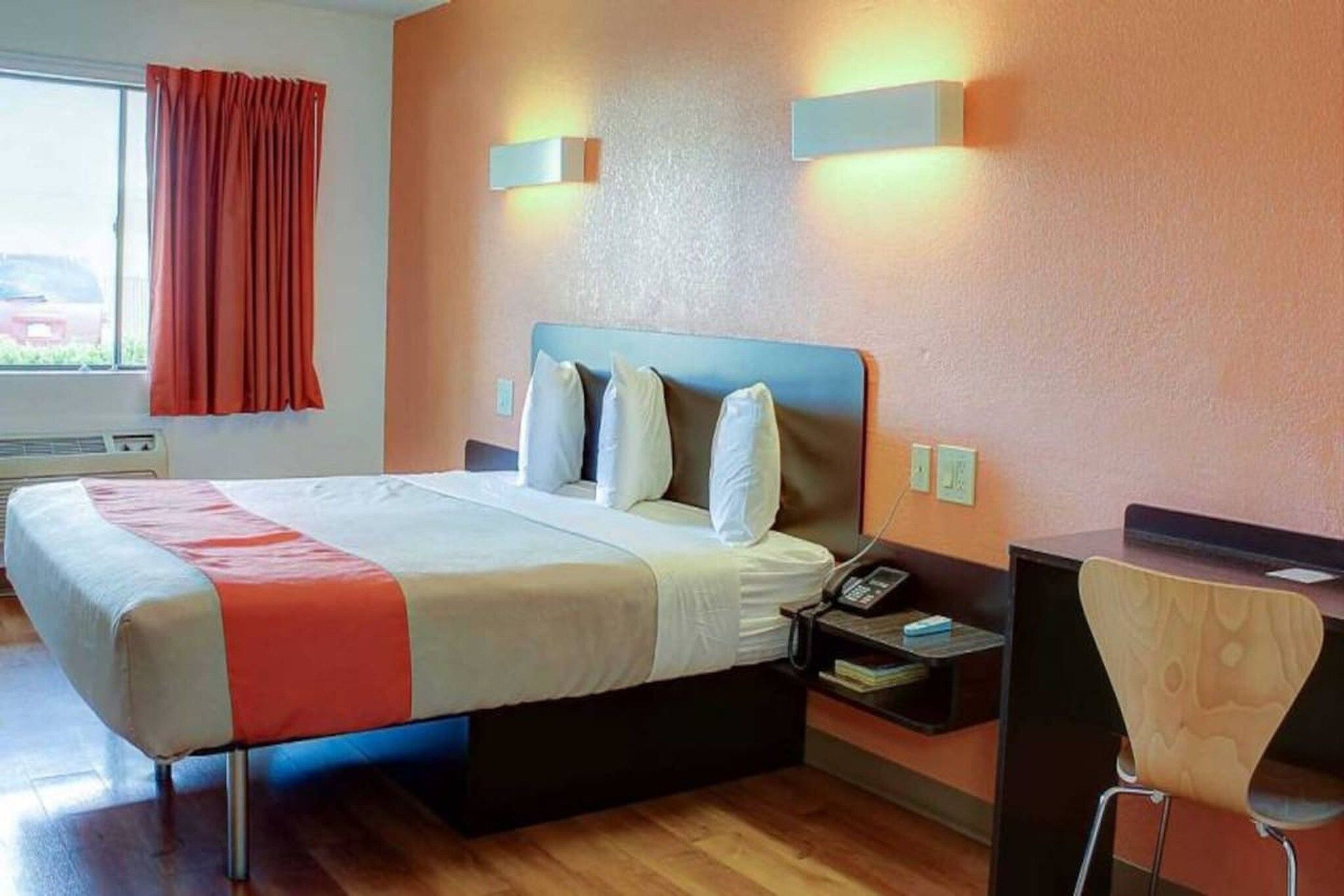 A hotel room with a bed, bedside tables, a desk, and a chair.