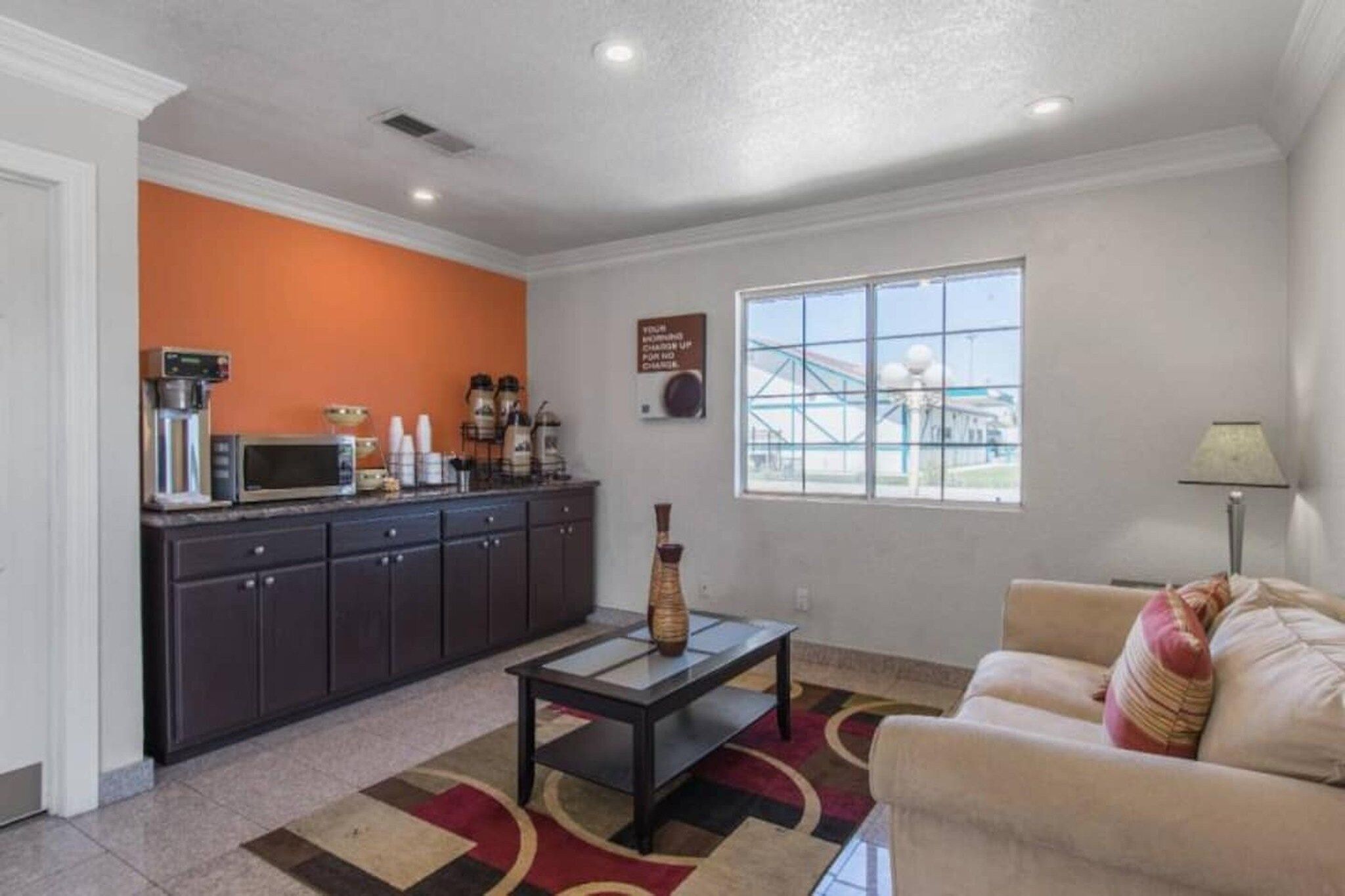 A compact living space with a kitchenette, a sofa, a coffee machine, and a window with a view.