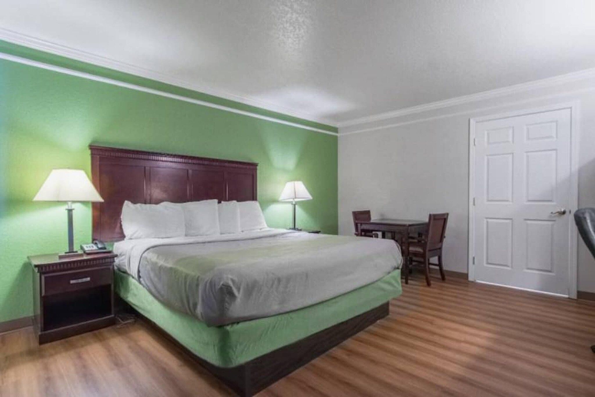 Una habitación de hotel con cama, mesitas de noche, escritorio y una silla.