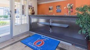 A reception area with a blue mat, a dark reception desk, and a plant. - 1 King Bed | Mobility Accessible Tub, Nsmk (Kingsburg)