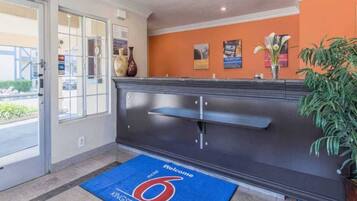 A reception area with a blue mat, a dark reception desk, and a plant.