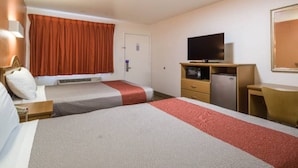 Quarto de hotel com duas camas, televisão, frigorífico e secretária.