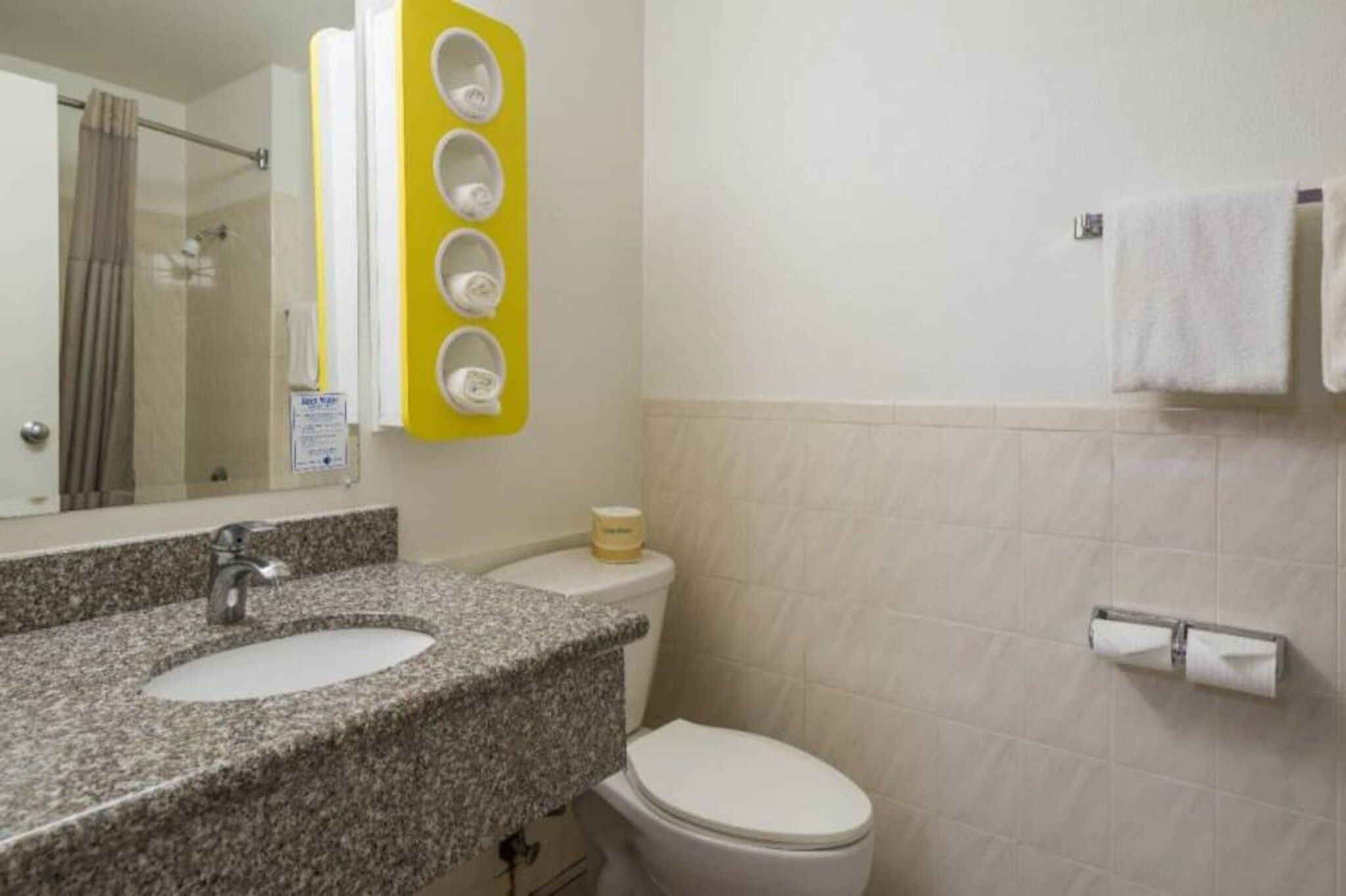 Un baño con lavamanos de encimera de granito, inodoro y espejo.