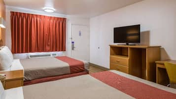 A hotel room with two beds, a television, a desk, and a chair.