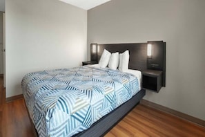 A modern bedroom with a patterned bedspread, a dark headboard, and bedside lamps.