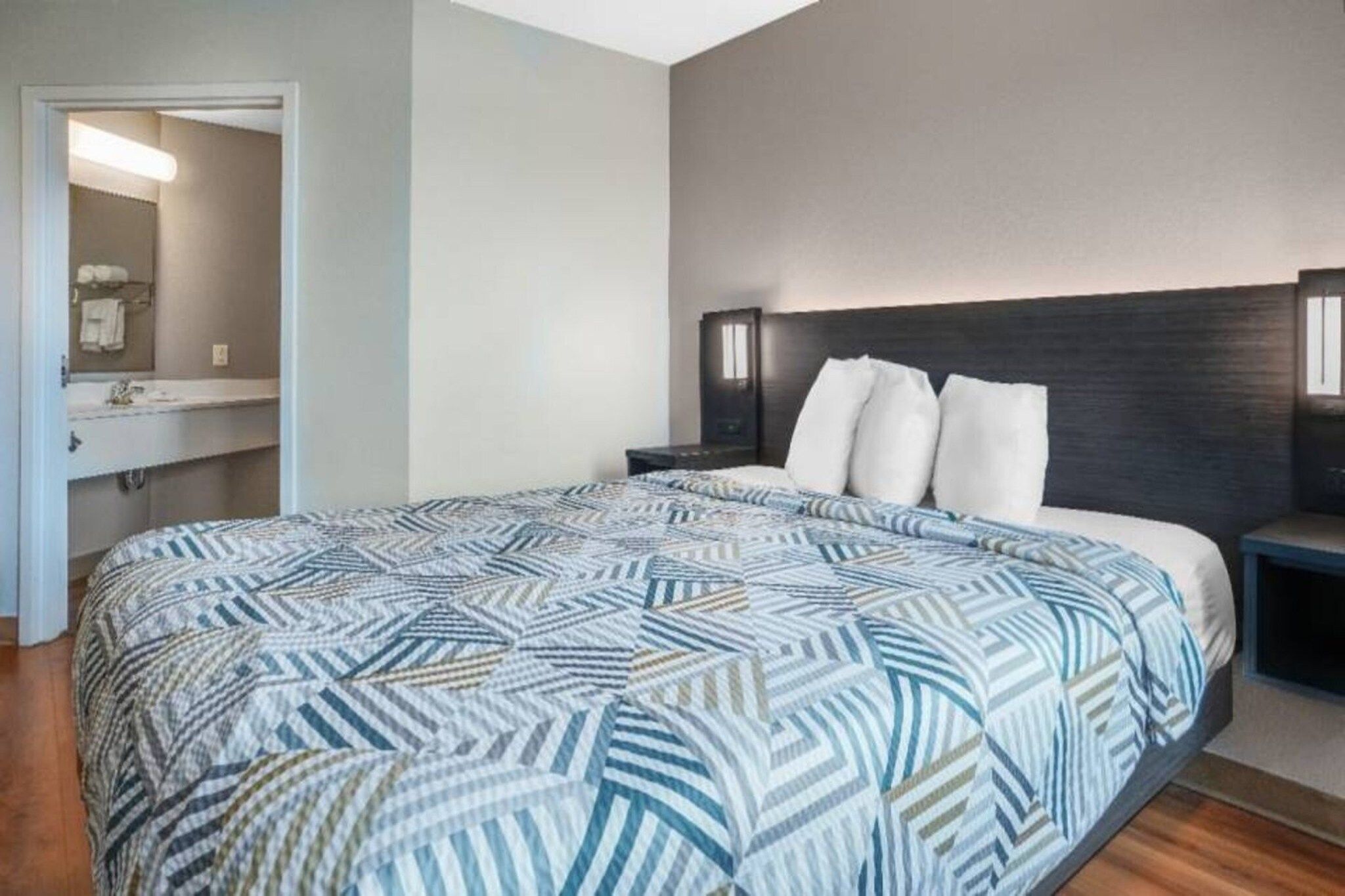 A bedroom with a bed, a nightstand, a dresser, and a mirror.