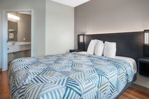 A bedroom with a bed, a nightstand, a dresser, and a mirror.
