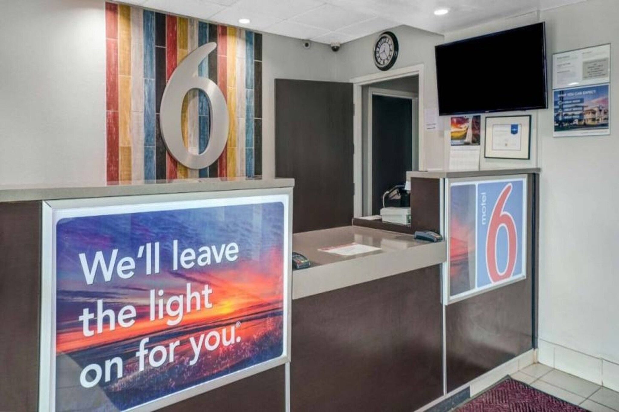 A hotel reception area with a large number '6' sign, a clock, and a motivational poster.