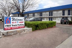 A motel with a sign advertising free truck parking, Wi-Fi, AARP membership, hot coffee, a swimming pool, and pet-friendly accommodations.