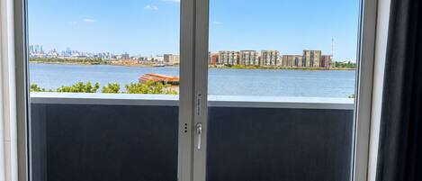 A balcony with a view of a river and cityscape, featuring two flower planters.