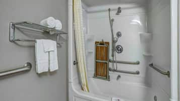 Une salle de bain équipée d’une baignoire, de barres d’appui, d’un rideau de douche et d’un porte-serviettes avec des serviettes.