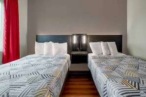 A hotel room with two beds, a nightstand, and a red curtain.