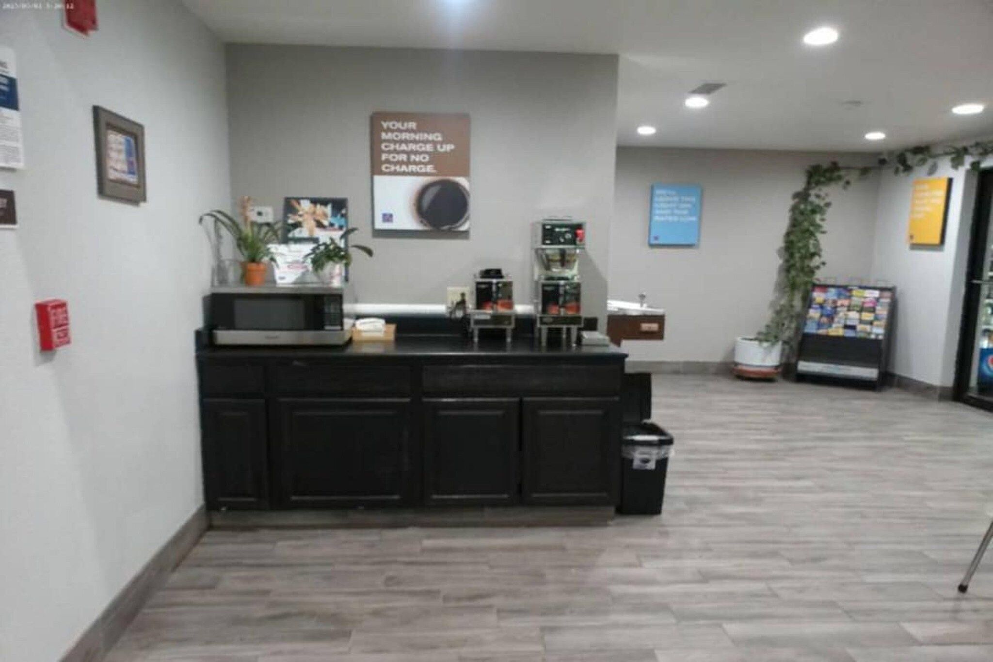 A reception area with a counter, a fire extinguisher, a sign, and a plant.