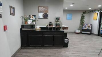 A reception area with a counter, a fire extinguisher, a sign, and a plant.