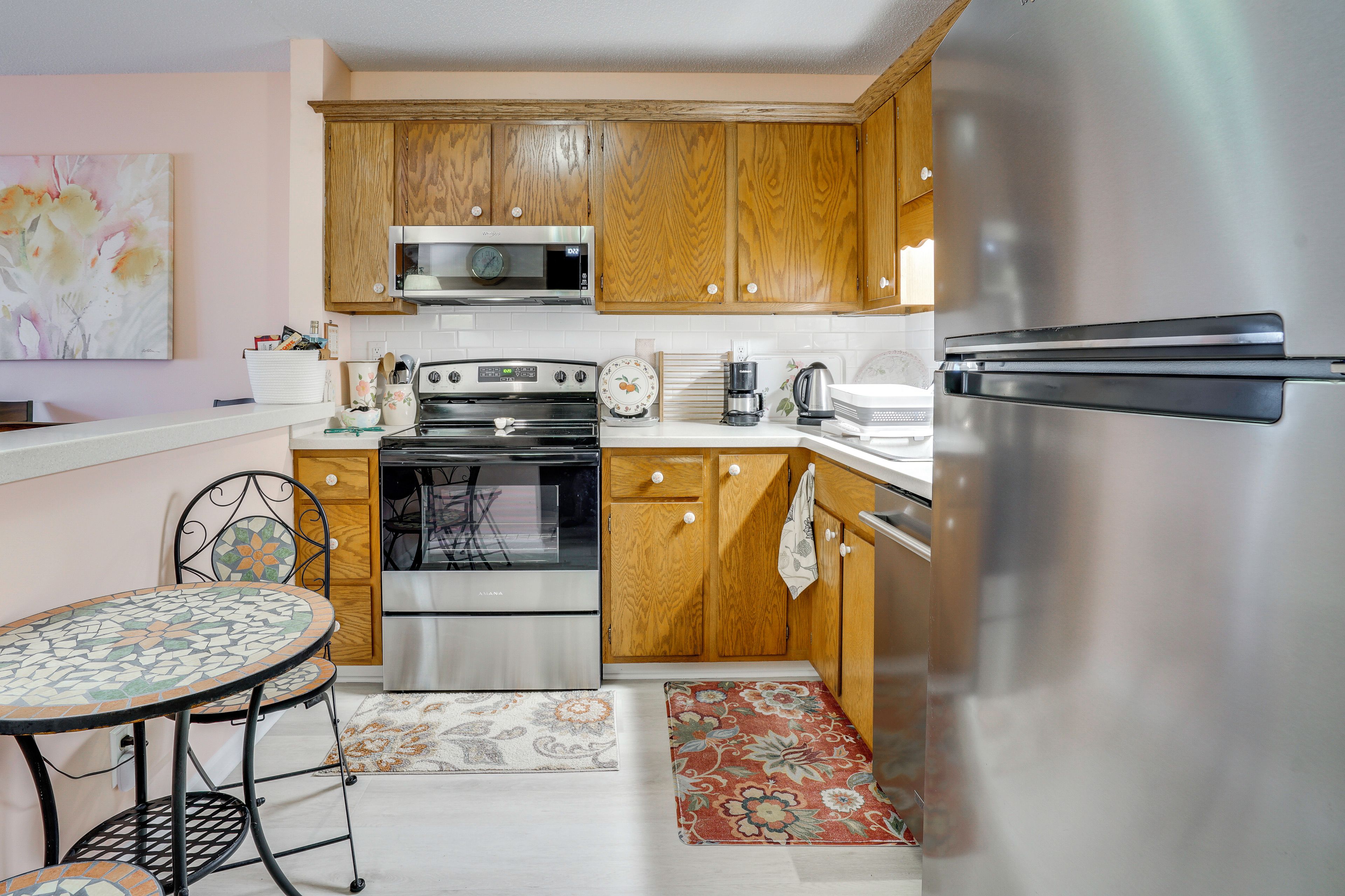 A compact kitchen with wooden cabinets, a stainless steel refrigerator, a microwave, an oven, and a coffee maker.