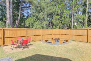 A backyard with a wooden fence, a fire pit, and outdoor furniture.
