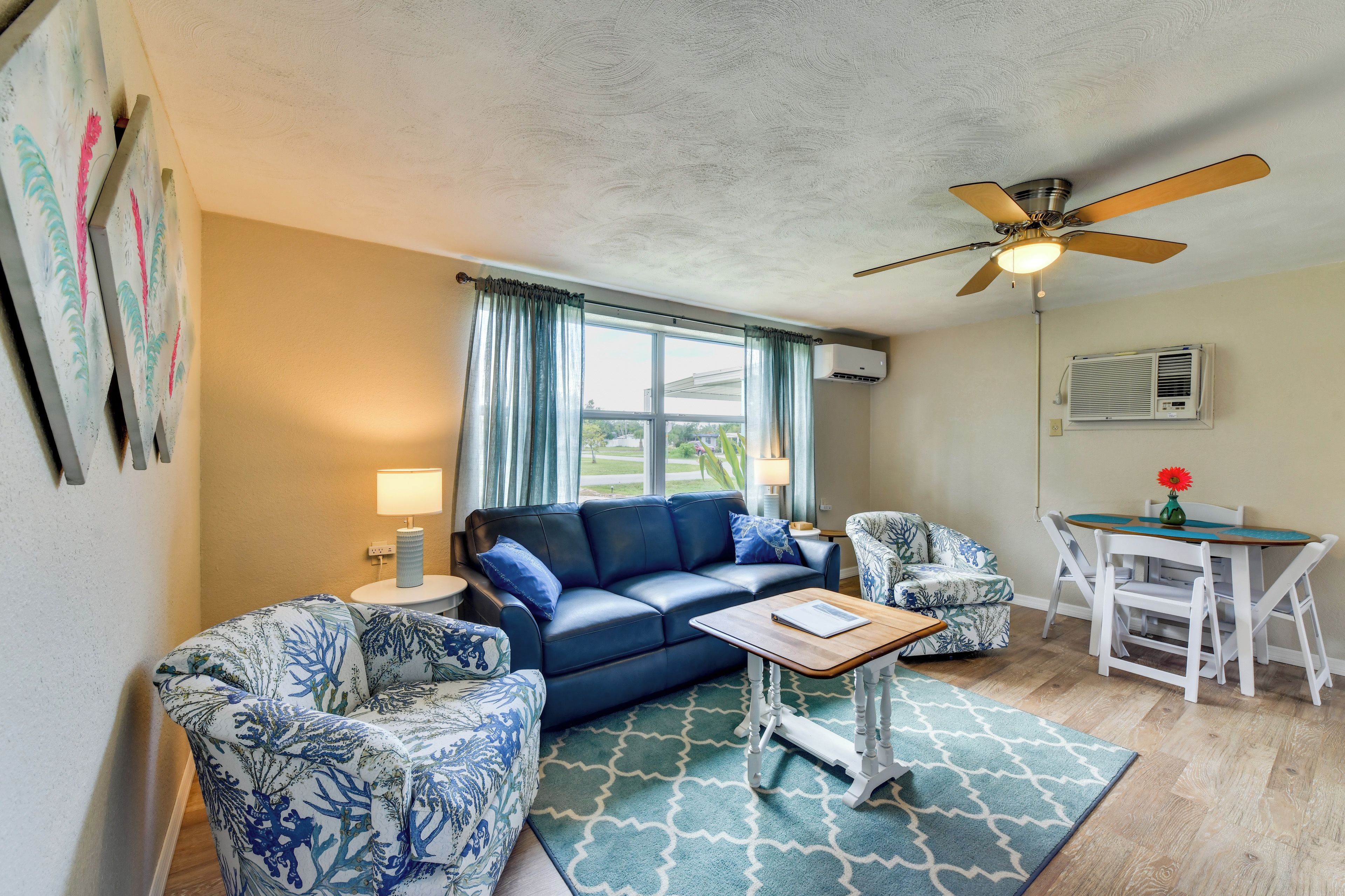 A living room with a blue sofa, patterned armchairs, a coffee table, and a dining table with chairs.