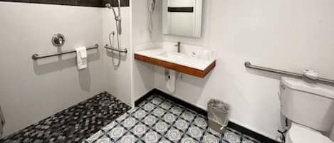Un baño con lavamanos blanco, espejo, inodoro y ducha.
