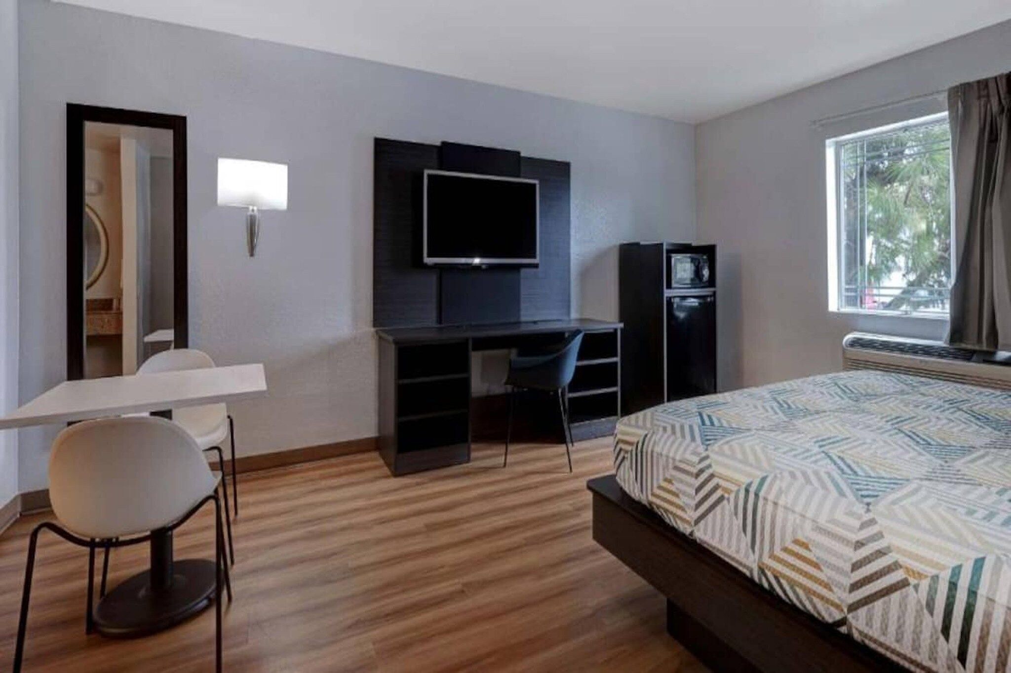 A hotel room with a bed, a desk with a chair, a television, and a wardrobe.