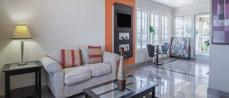 Una sala de estar moderna con un sofá, una mesa de centro, una lámpara y un televisor.