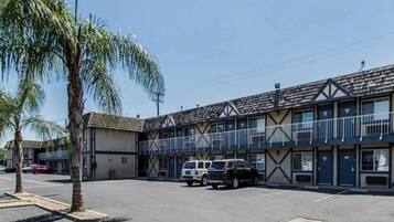 A motel with a parking lot, two-story buildings, and a palm tree.