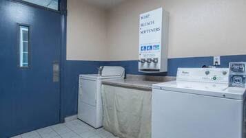 A laundry room with a washing machine, dryer, and a sign indicating the availability of soap, bleach, and softeners.