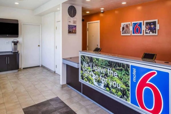 Mostrador de recepción de un motel con un gran letrero que dice 'Dejaremos la luz encendida para ti'.
