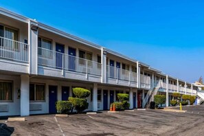Un motel con una hilera de habitaciones, cada una con puerta y un pequeño balcón.