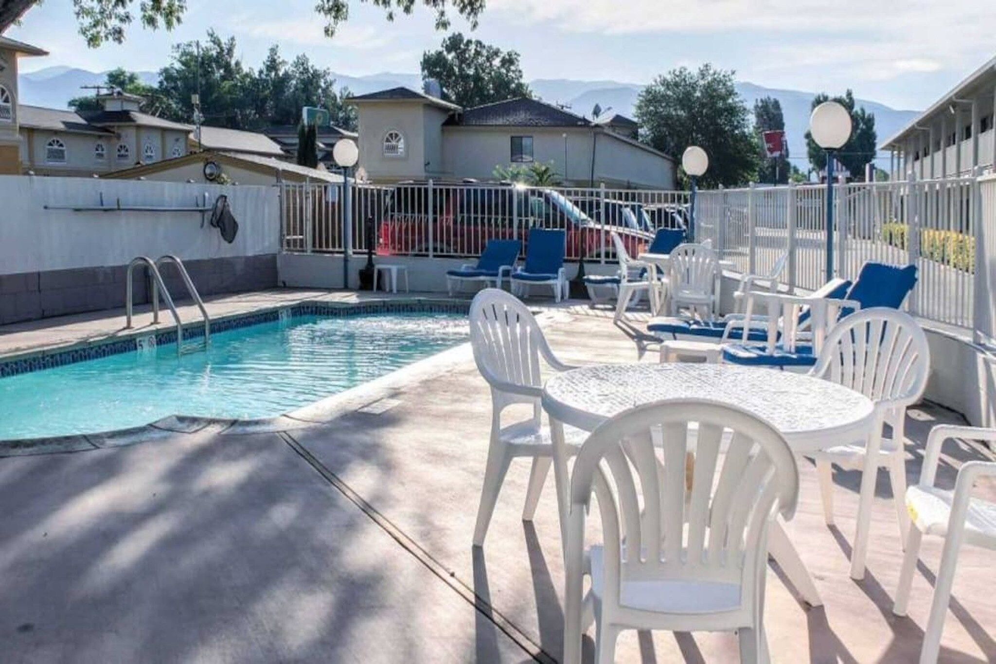Une piscine dotée d’un espace ombragé, de chaises longues et d’une table.