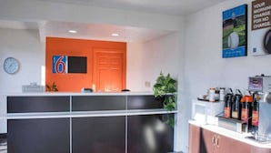 Un área de recepción con mostrador, un reloj y un letrero con el número 6.