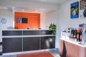 Un área de recepción con mostrador, un reloj y un letrero con el número 6.