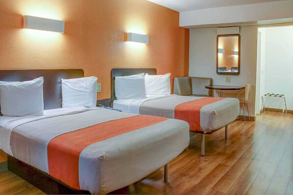 Una habitación de hotel con dos camas, una mesita pequeña y una silla.