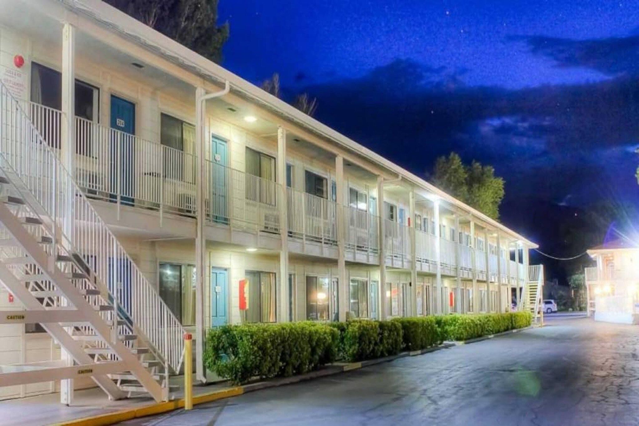 Ein Motel mit mehreren Etagen, Außenstairnellen und einer gut beleuchteten Fassade.